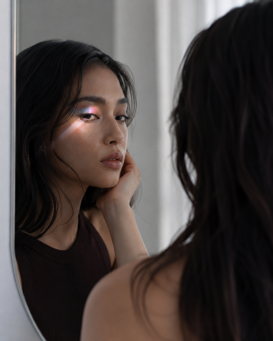 Woman noticing her multichrome eye makeup changing in the mirror